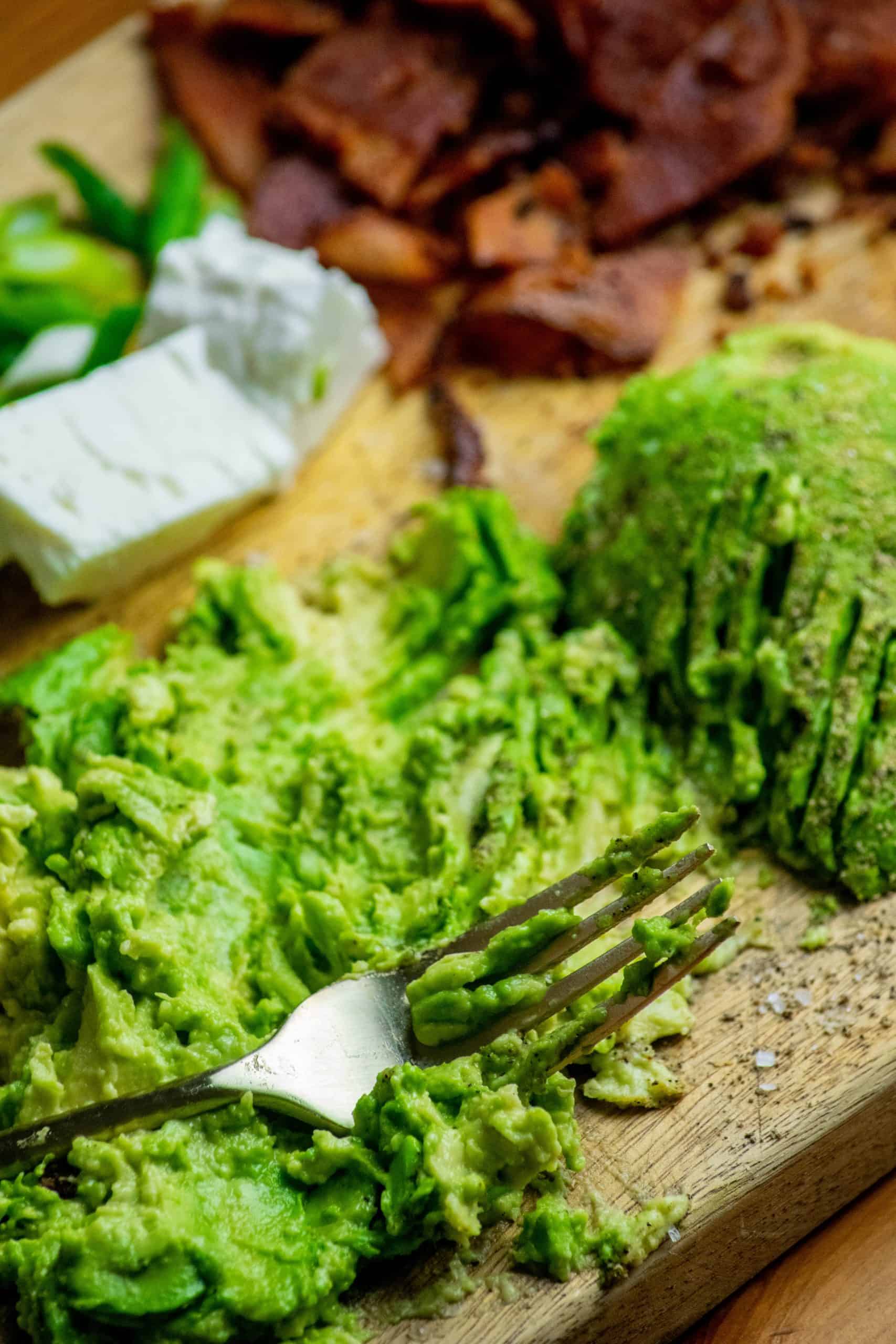 Mash the avocado. Season the avocado with salt, pepper, and garlic powder, then mash with a fork.