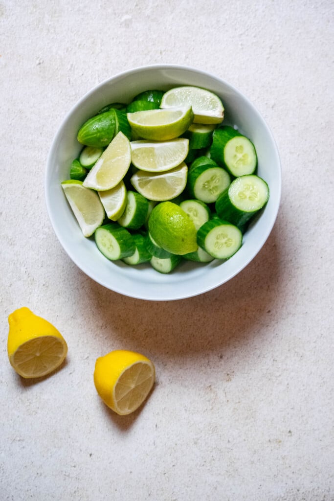 cut cucumbers into small pieces, cut limes into 4 quarters, and cut lemon in half. 