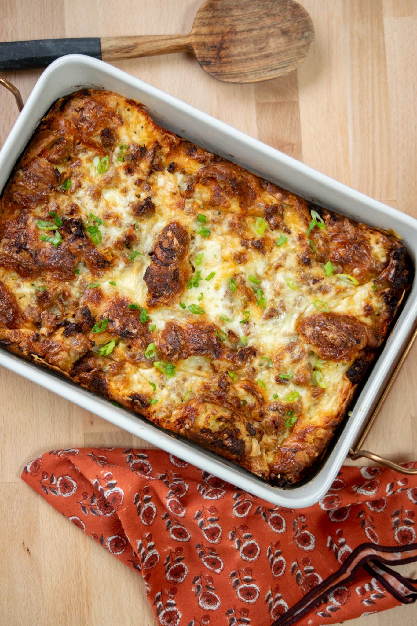 Baked croissant breakfast casserole with sausage and Gruyère in a casserole dish.