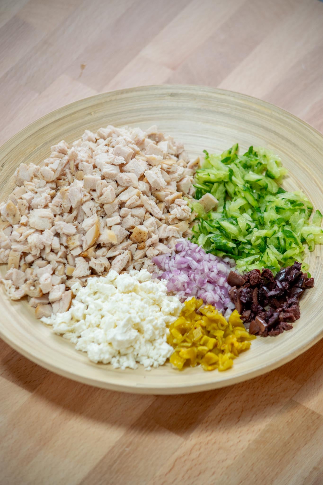 Add the chopped chicken, grated cucumber, pepperoncini, shallot, feta and olives to a mixing bowl.