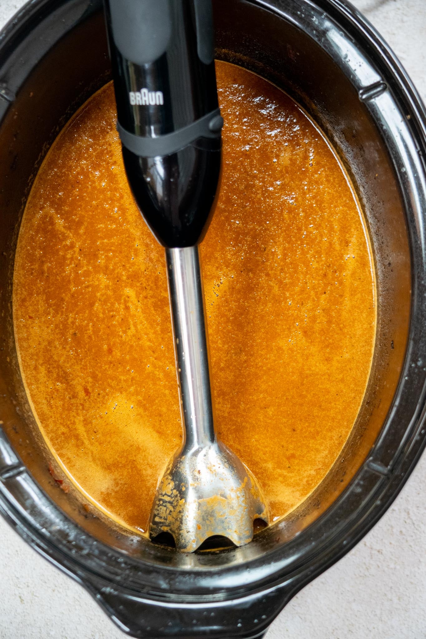 Blend the consommé (optional).
Remove the cinnamon sticks and bay leaves. Blend the cooking liquid until smooth for a rich, flavorful sauce.