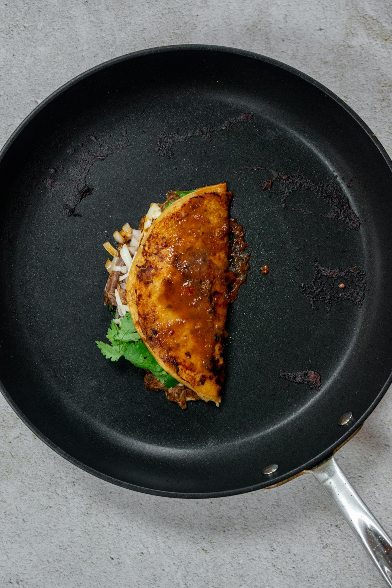 Gently fold over into a half-moon shape. Add a small ladle of consommé to the top of the tortilla.