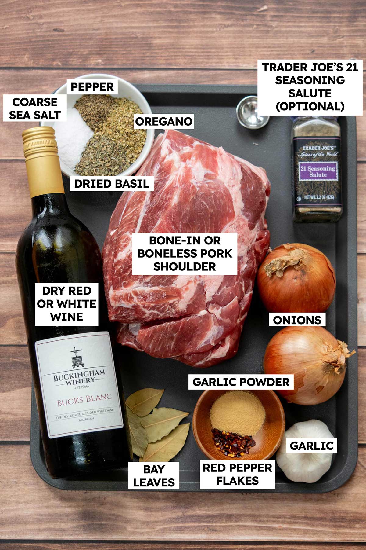 Overhead view of ingredients for slow cooker Italian roast pork, including pork shoulder, onions, garlic, wine, bay leaves, and Italian herbs and spices.