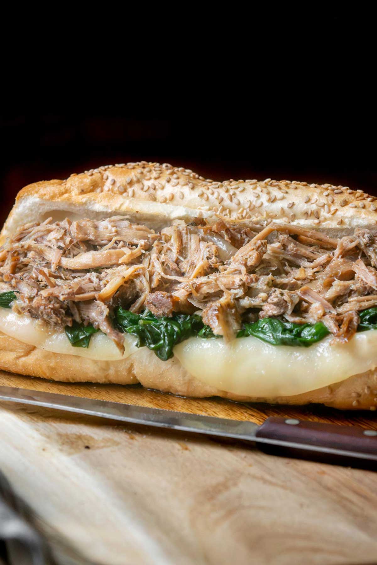 Assemble the sandwiches. Pile the warm Italian roast pork onto seeded rolls, top with sharp provolone, and let the cheese melt into the pork. Finish with garlicky spinach or broccoli rabe and a long hot if you like some heat.