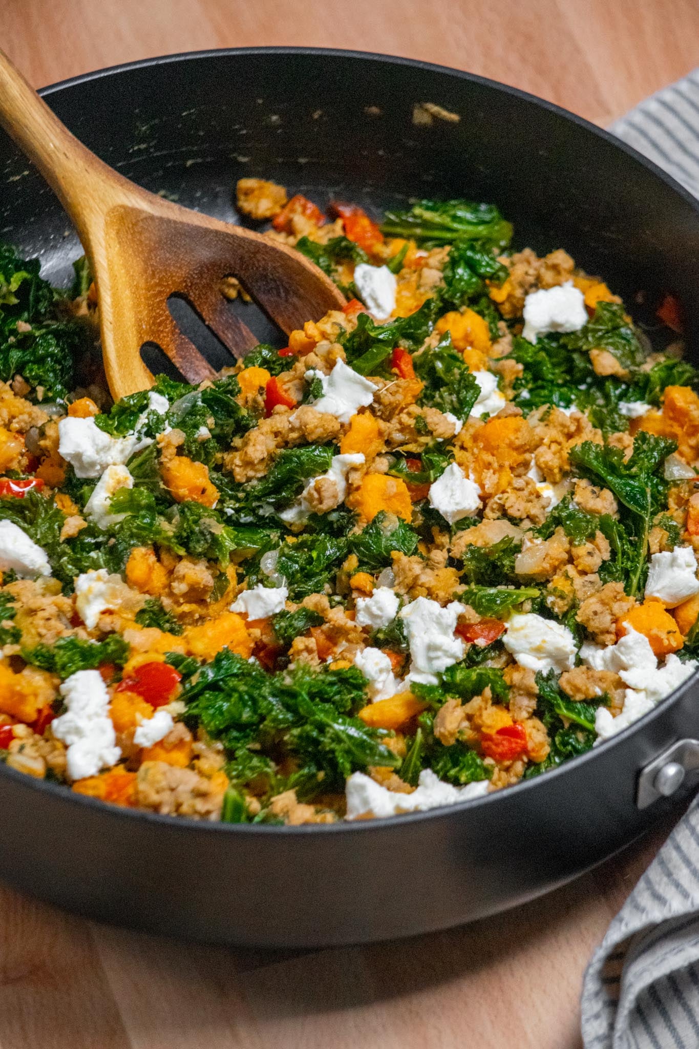Ground turkey skillet meal with sweet potatoes, kale, red peppers and goat cheese in a skillet.