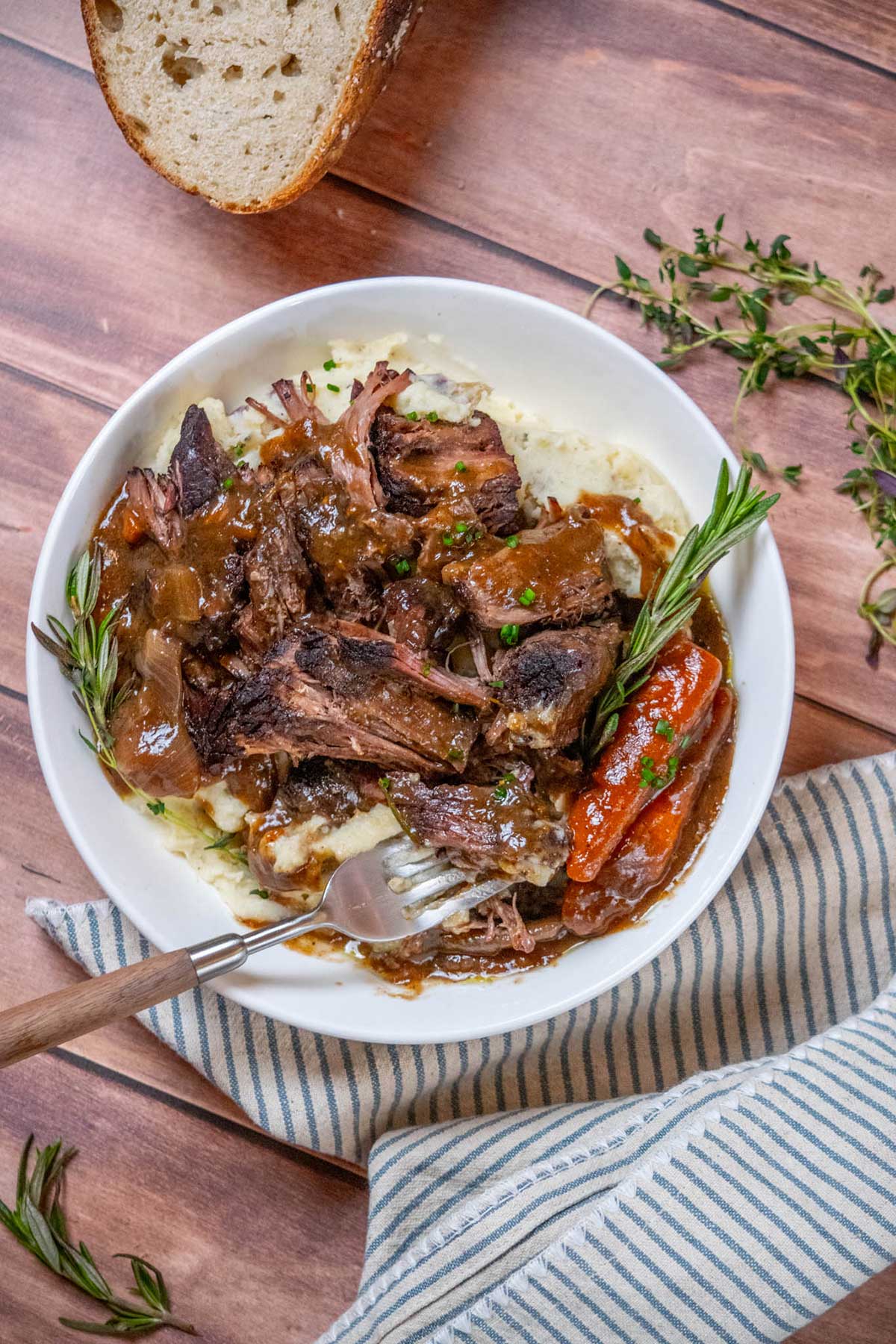 Dutch Oven Chuck Roast plated with carrots, gravy, and mashed potatoes.