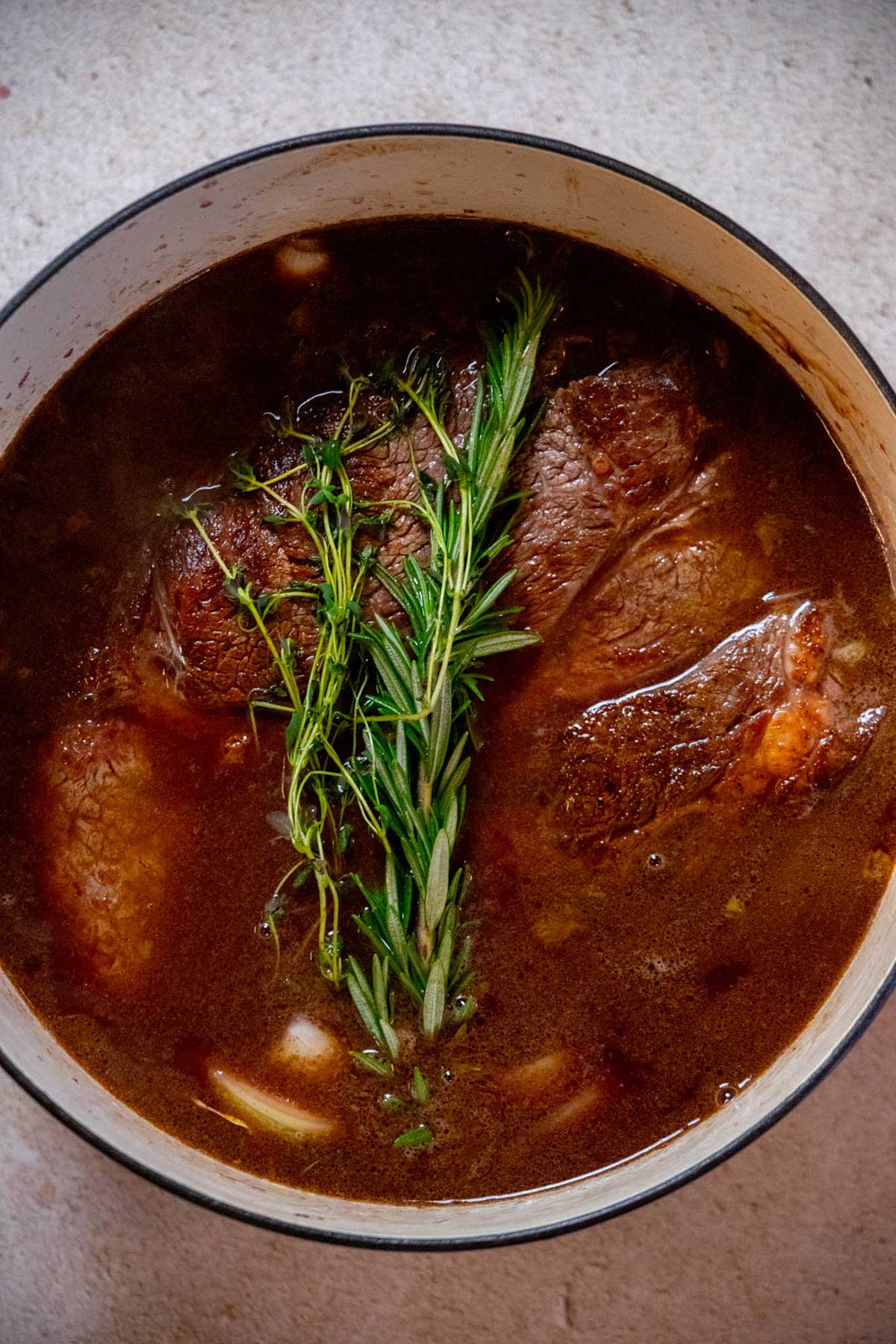 Pour in the beef stock, then transfer the Dutch oven to the preheated oven and cook for 3 hours.
