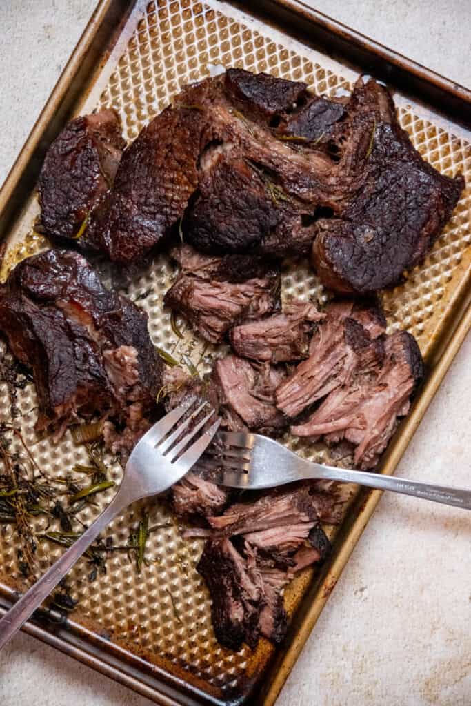 Remove the beef from the dutch oven with tongs, and transfer to a plate or sheet pan. Shred the beef with 2 forks, discarding any fat or connective tissue. 