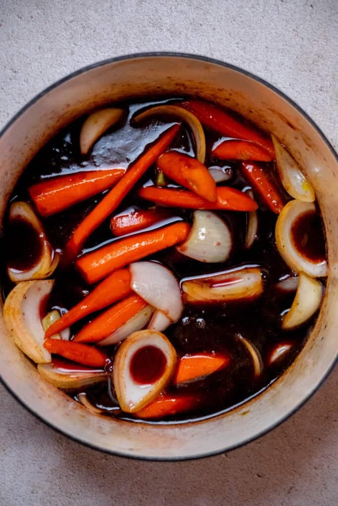 Once the veggies are lightly browned, add the red wine to the pan, and use a wooden spoon or spatula to scrape up any browned bits from the bottom (that's flavor!). 