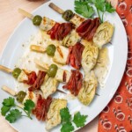 Halloumi Skewers (Grilled Antipasto Skewers) on a plate with dressing and parsley.