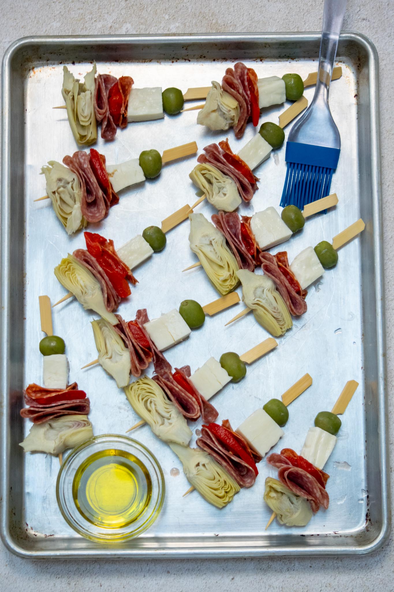 Thread skewers with an olive, a piece of halloumi,, assorted meats, red pepper, artichoke halves. Be gentle and hold the halloumi firmly on the sides when threading to prevent cracking. 