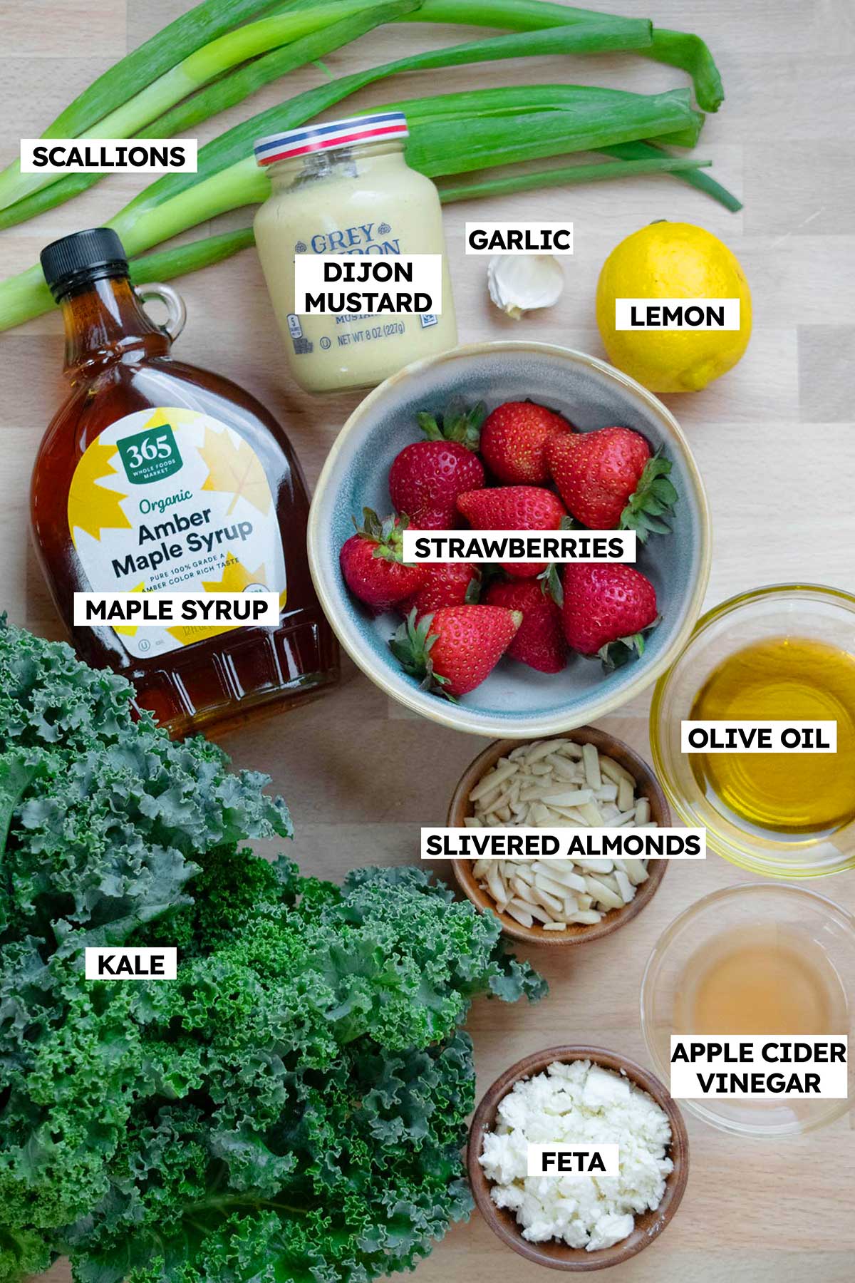 Easy Kale Salad ingredients- kale, strawberries, feta, olive oil, apple cider vinegar, lemon, garlic, dijon, maple syrup, slivered almonds, scallions.