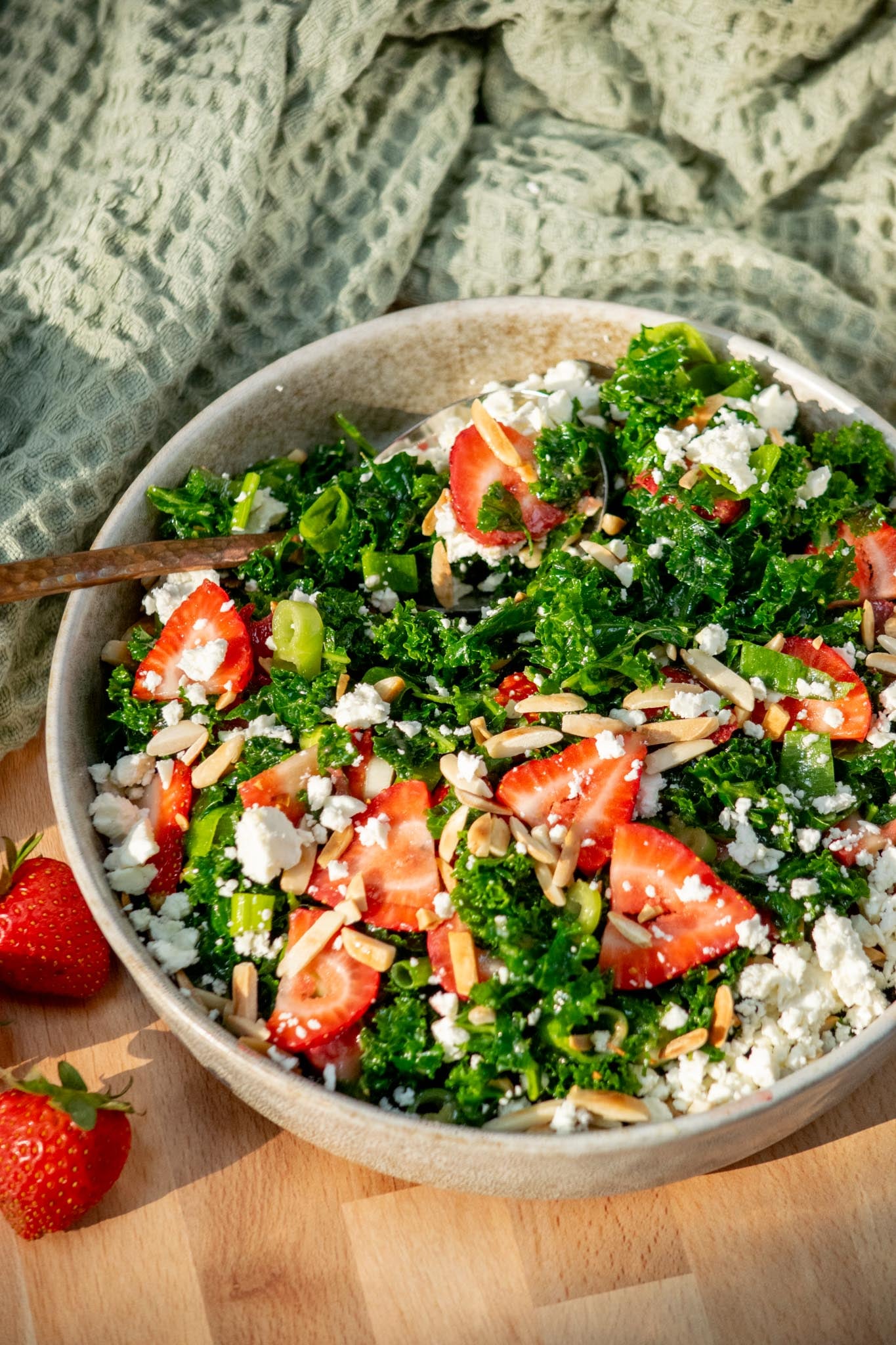 bowl of Easy Kale Salad with Strawberries and Feta in a serving bowl with spoon.