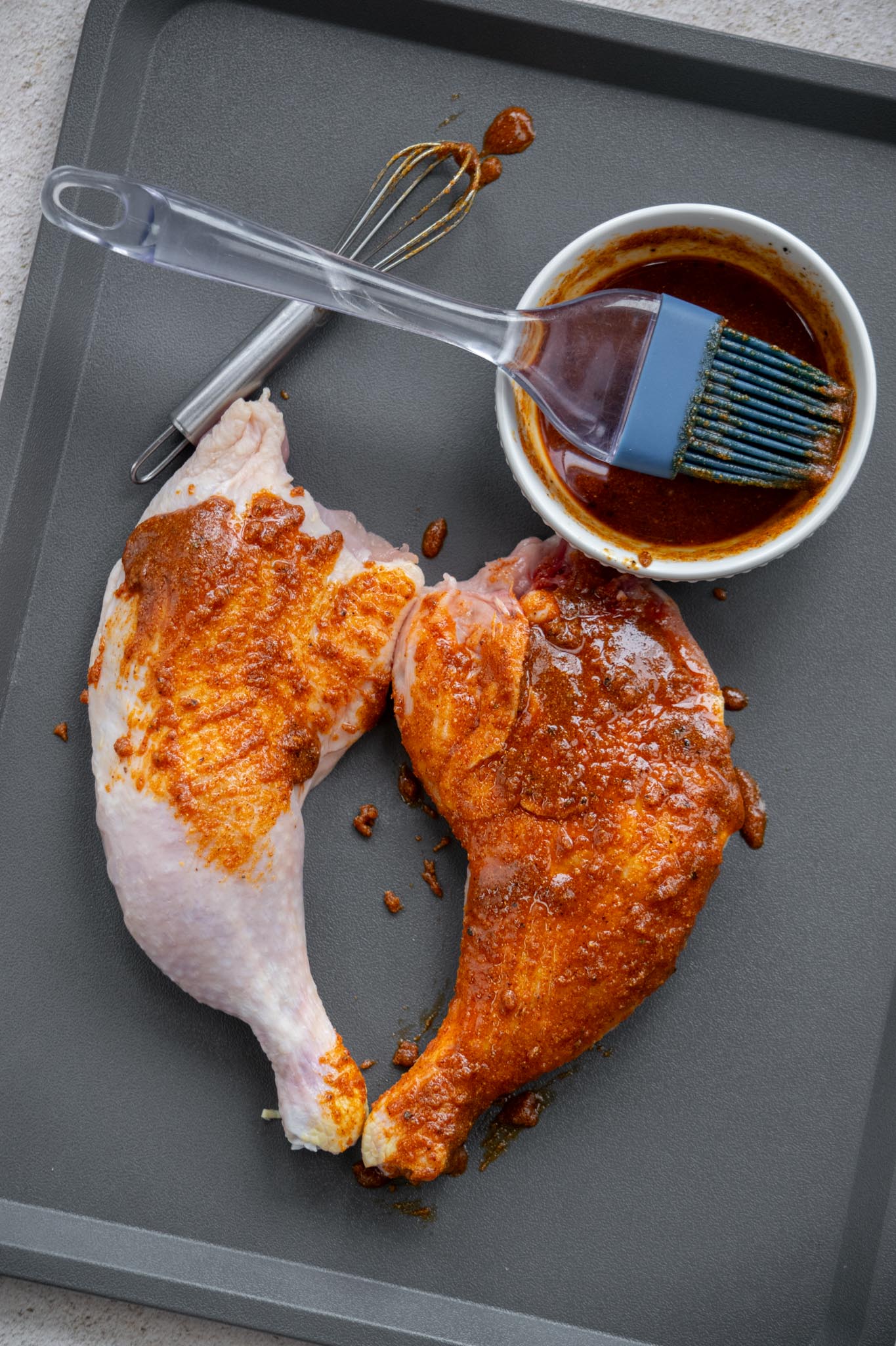 Mix spices together, then whisk together with olive oil, and brush in an even layer on both side of the chicken leg quarters, being careful to make it even so no clumps of the spice paste remain, as they can burn in the air fryer. 