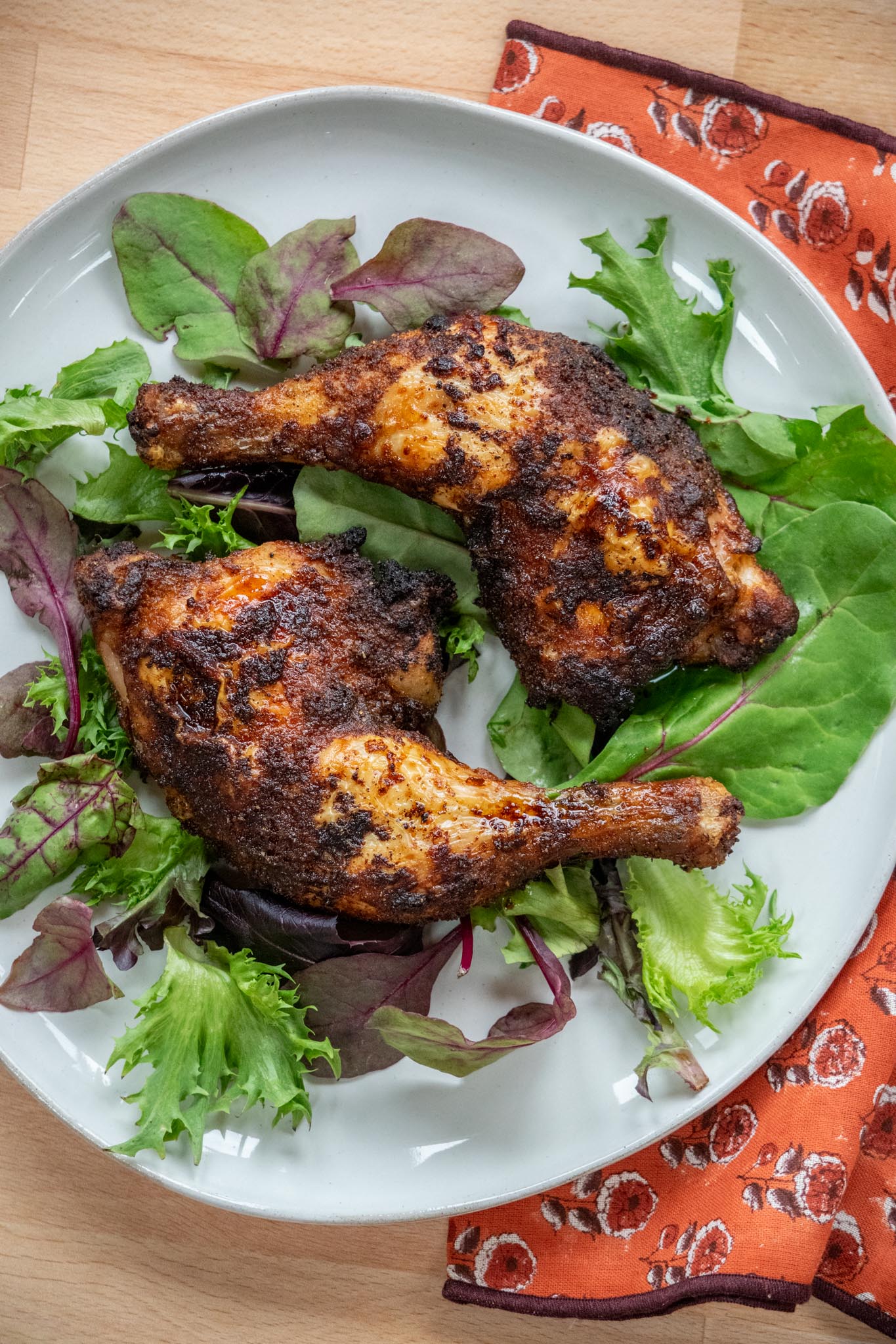 Air Fryer Chicken Leg Quarters on.a plate with mixed greens. 