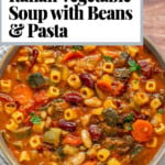 Pinterest pin for hearty Italian vegetable soup with beans and pasta, featuring vegetarian minestrone soup in a rich tomato broth with zucchini, carrots, and cubetti pasta.
