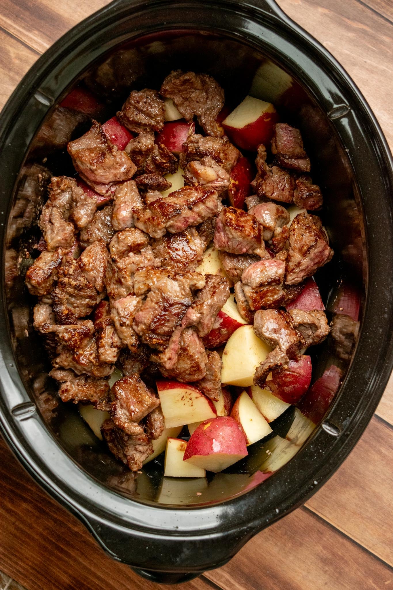 Prep the potatoes and brown the beef. Cut the potatoes into bite-sized pieces, peeling them first if using russets, and add them to the slow cooker. Heat the oil and butter in a skillet over medium-high heat. Toss the beef with 2 tablespoons of flour and season with salt and pepper. Brown the beef in 2–3 batches for 2–3 minutes per side, until nicely browned but not cooked through. Transfer to the slow cooker.