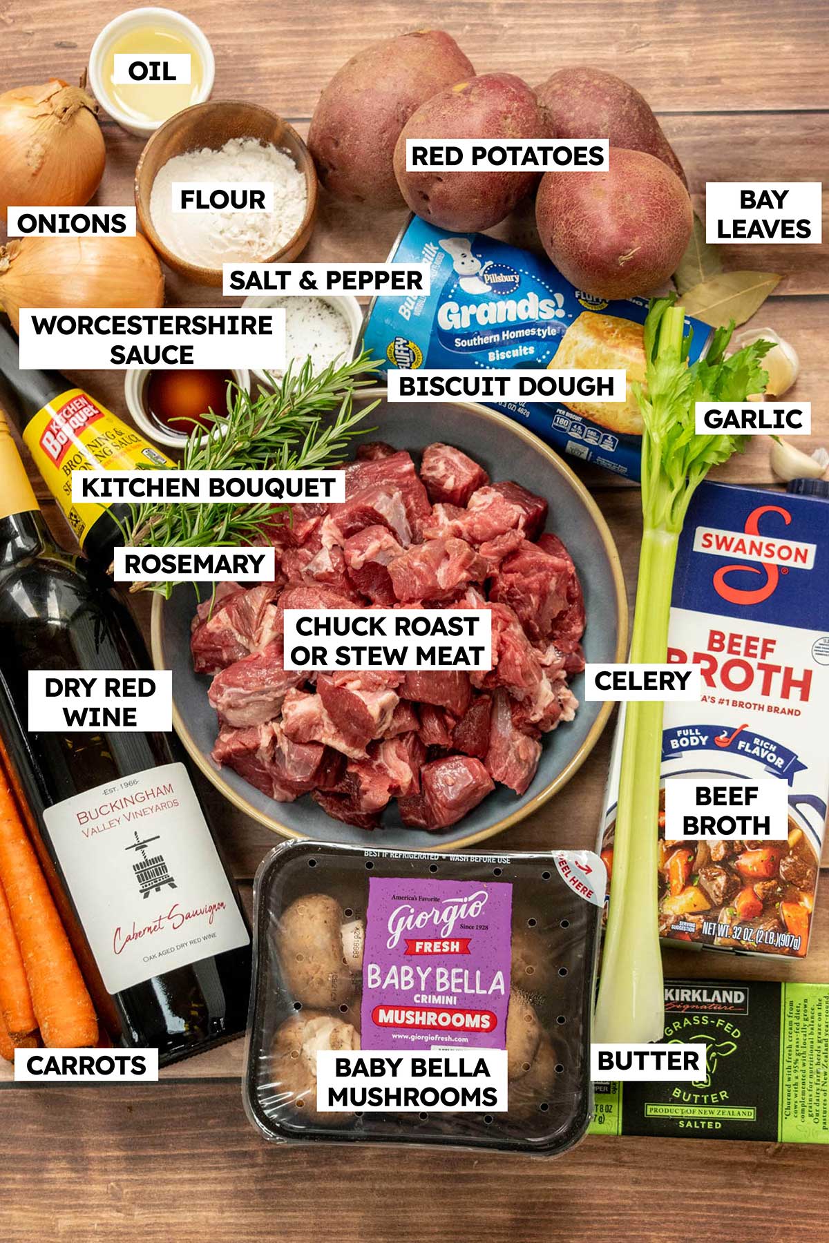 Labeled ingredients for slow cooker beef stew and dumplings, including chuck roast, red potatoes, carrots, mushrooms, beef broth, red wine, and refrigerated biscuit dough.