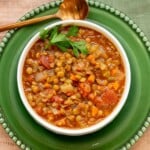 Easy green lentil soup with carrots, celery, fire-roasted tomatoes, and parsley in a white bowl.