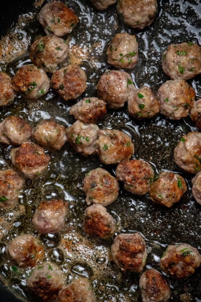in a large frying pan, heat olive oil over medium heat and brown the meatballs in batches on both sides.
