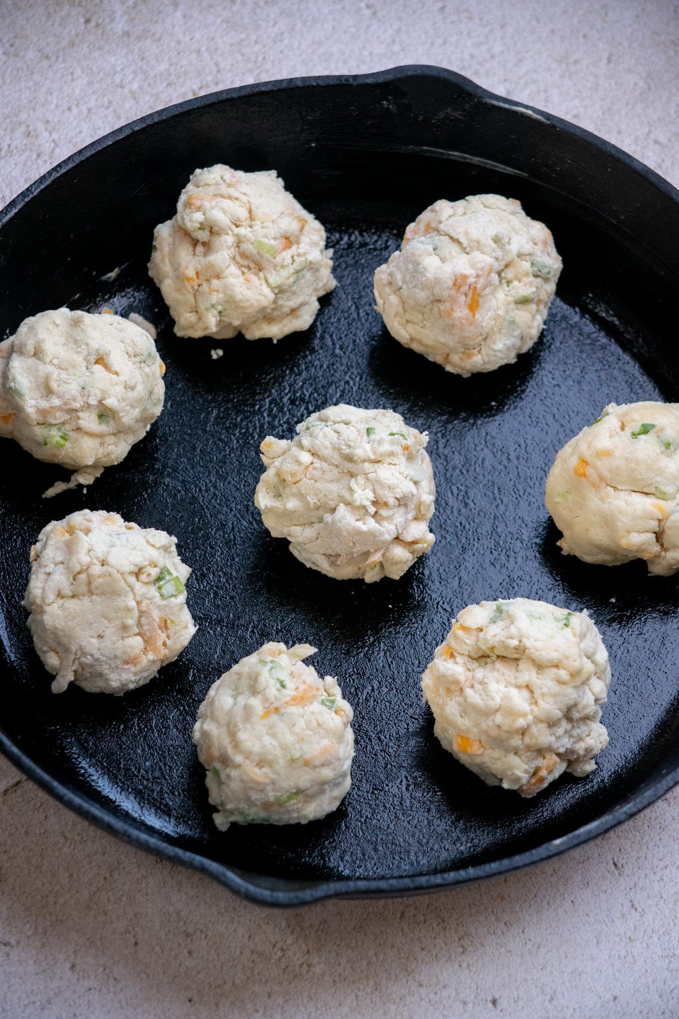 Divide the dough into 8 even pieces, gently shape and flatten into biscuits, then transfer to a greased large baking dish or 12-inch cast iron skillet.