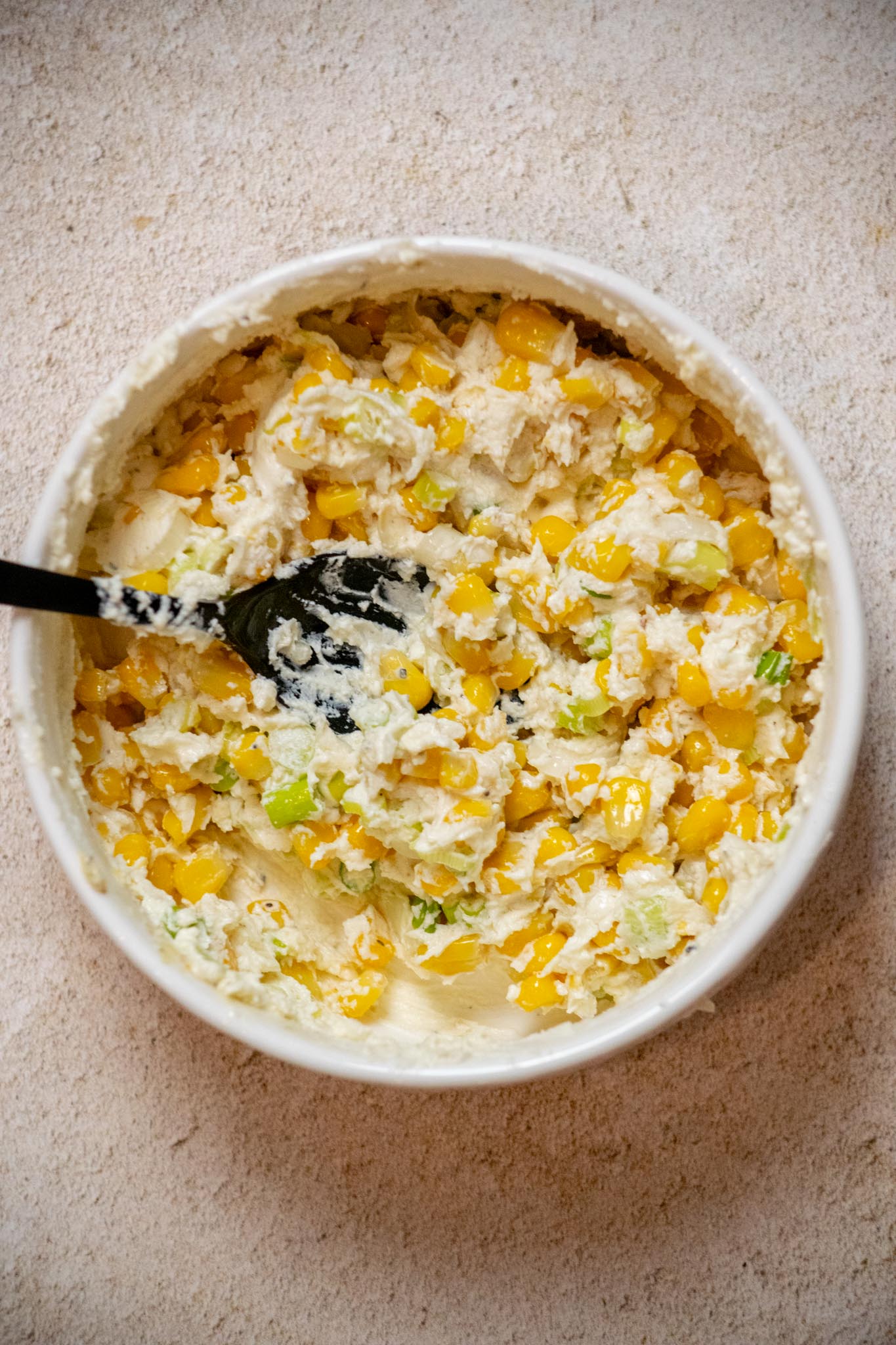Add corn to a mixing bowl with sliced scallions and goat cheese, and stir to combine.