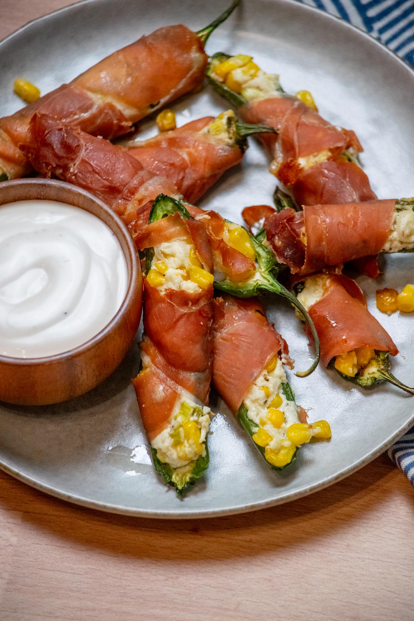 Goat Cheese Jalapeño Poppers with Prosciutto and Sweet Corn on a pate with a bowl of ranch.