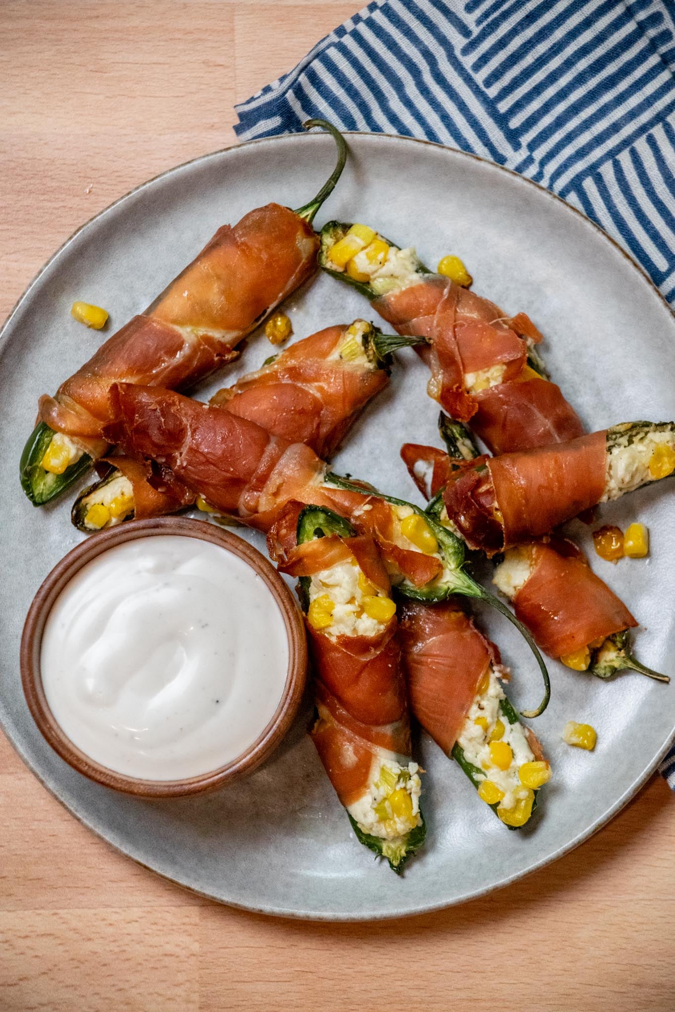 Goat Cheese Jalapeño Poppers with Prosciutto and Sweet Corn on.a plate with a side of ranch dressing.