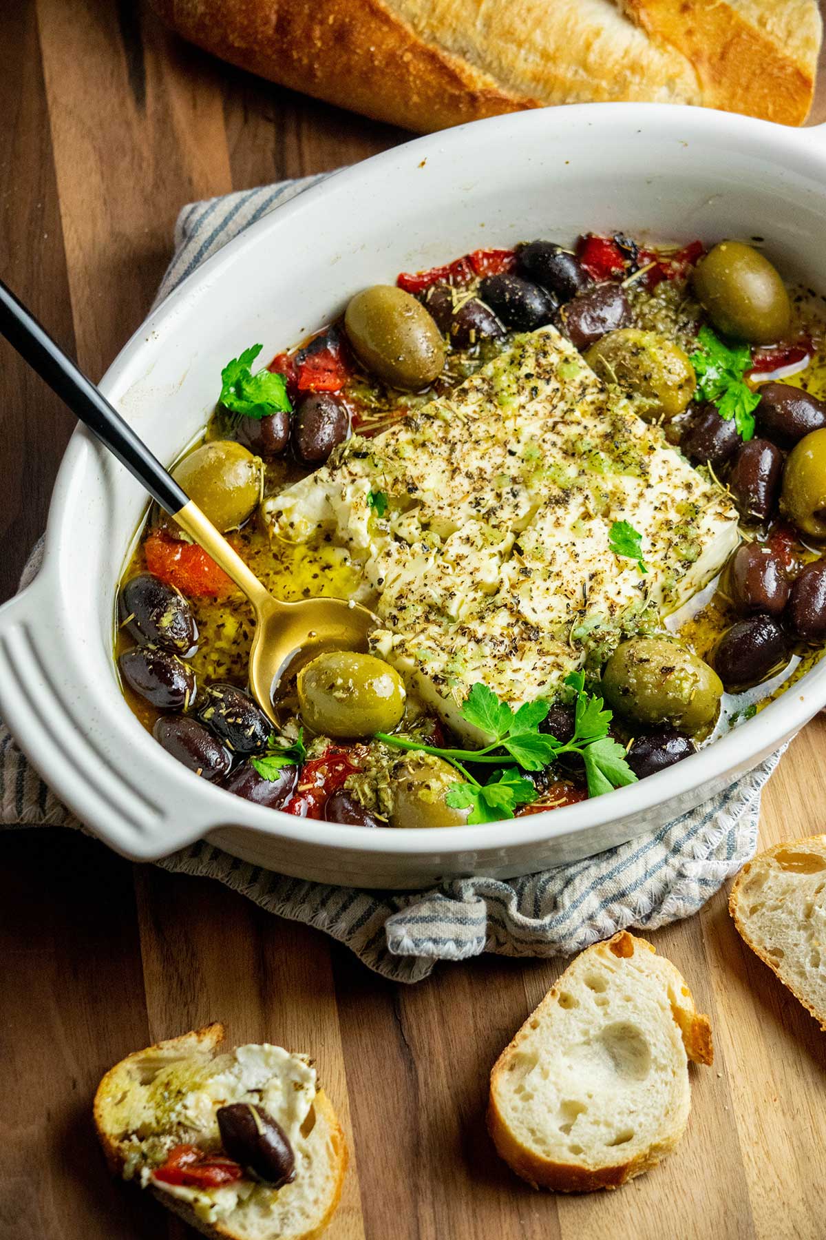 Easy Baked Feta recipe in baking dish with bread on the side.