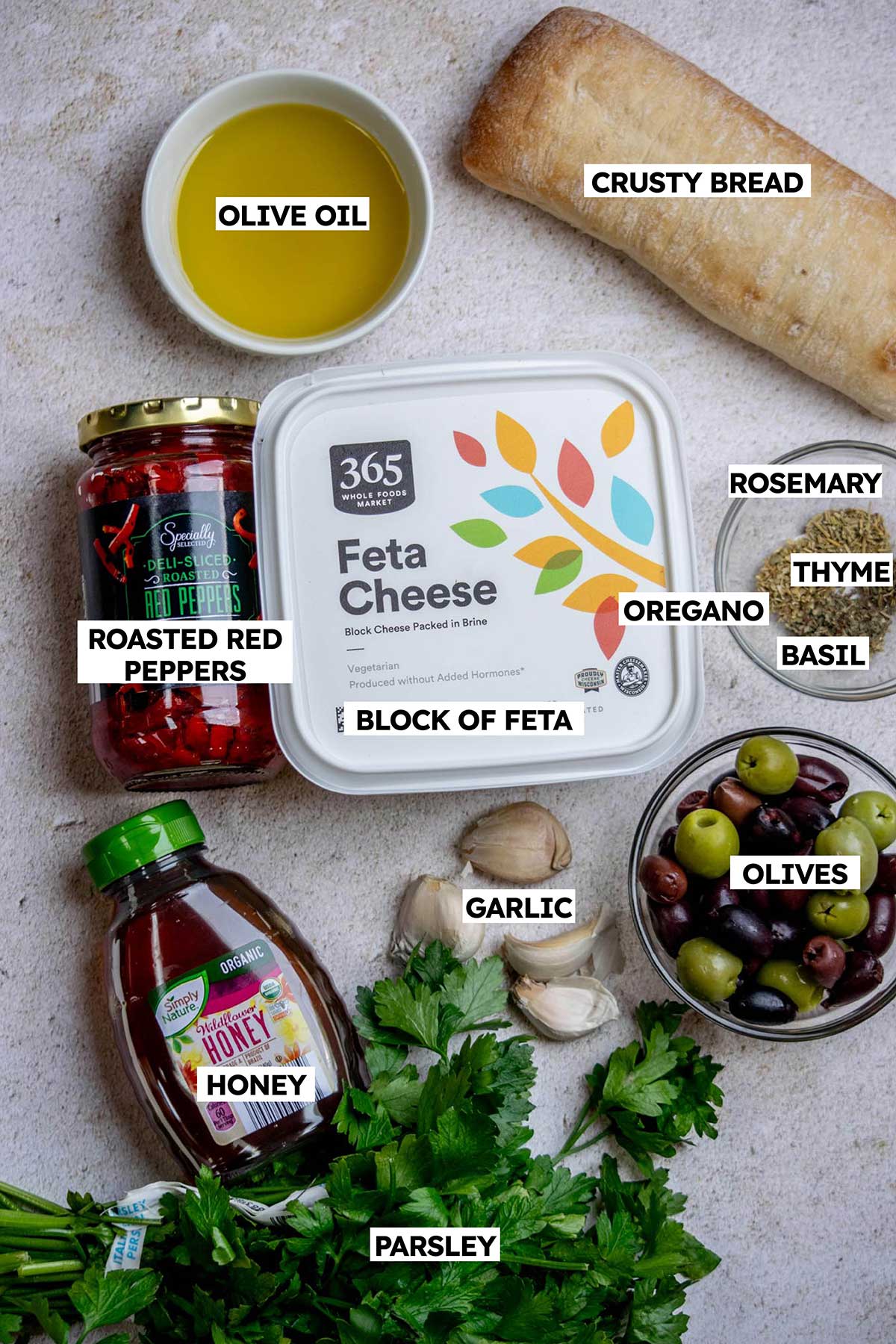 Easy Baked Feta Recipe ingredients- feta, herbs, honey, olive oil. olives, garlic, roasted red peppers.
