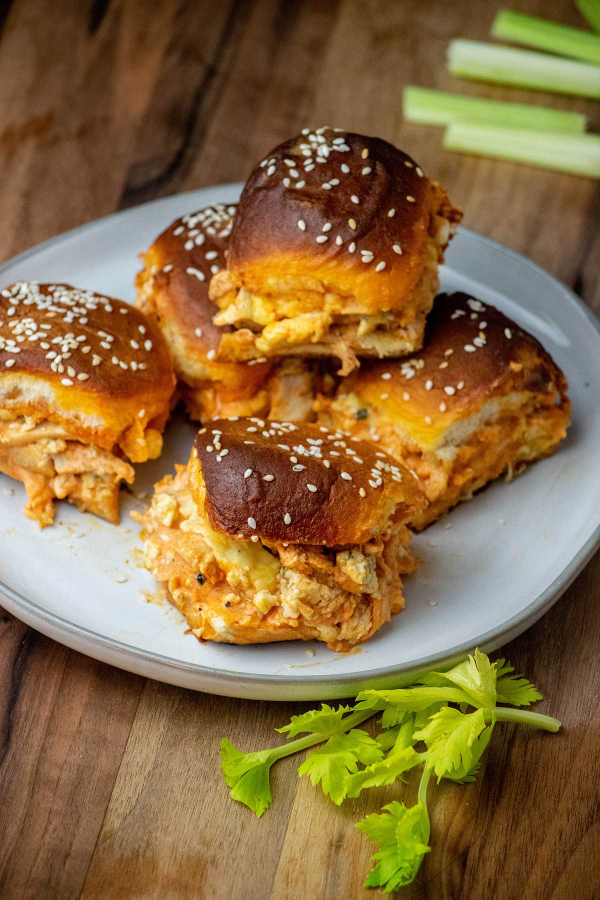 Buffalo chicken slider with shredded chicken, melted cheese, blue cheese crumbles, and sesame-topped Hawaiian rolls.
