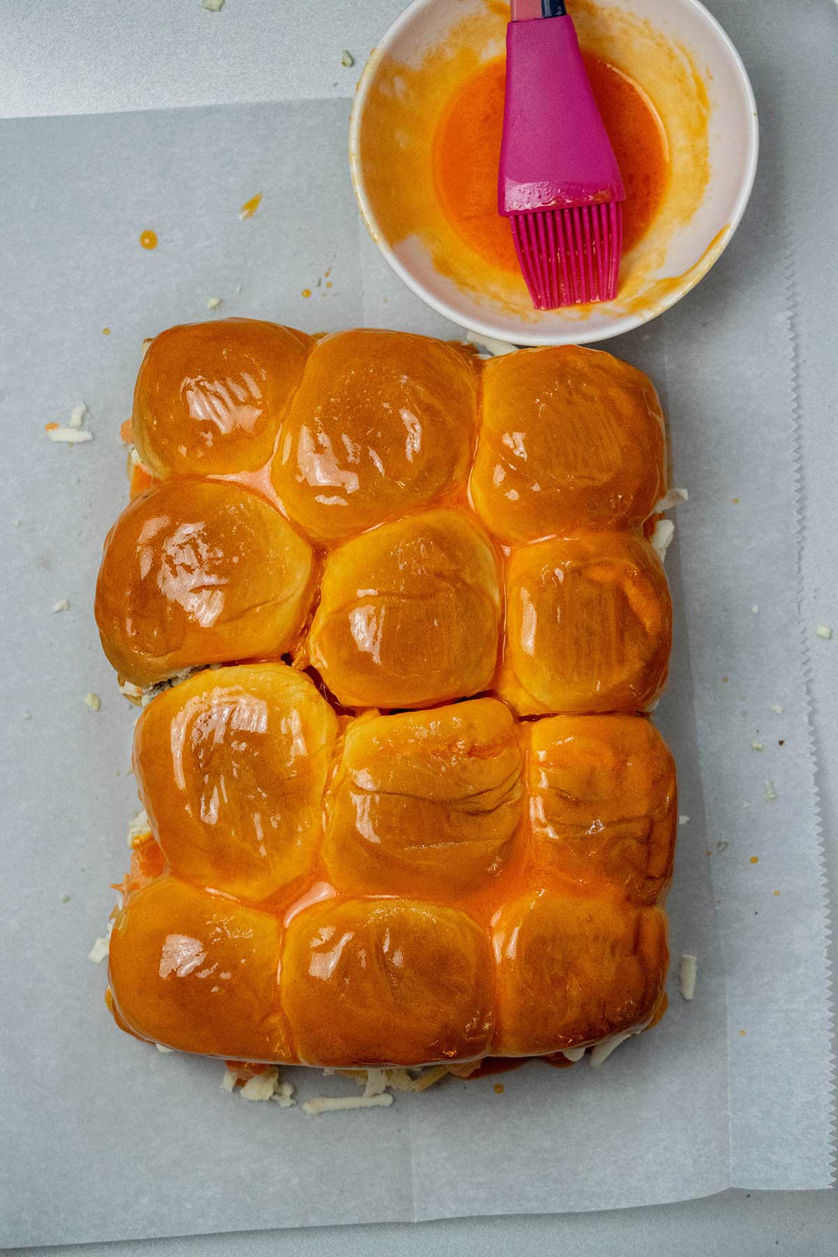 Add the hot sauce butter.
Mix the melted butter with hot sauce, brush it over the tops of the rolls, and sprinkle with sesame seeds.
