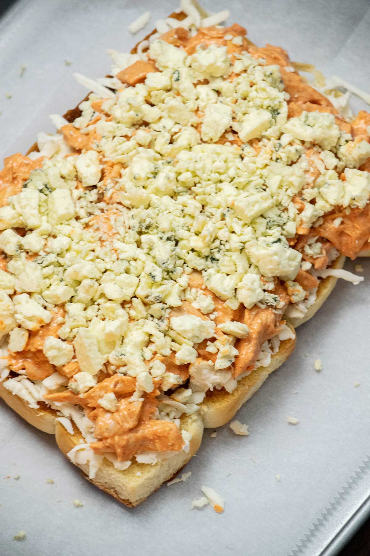 Assemble the sliders.
Layer smoked mozzarella over the bottom rolls, then add the buffalo chicken mixture and blue cheese crumbles. Place the top half of the rolls over the filling.