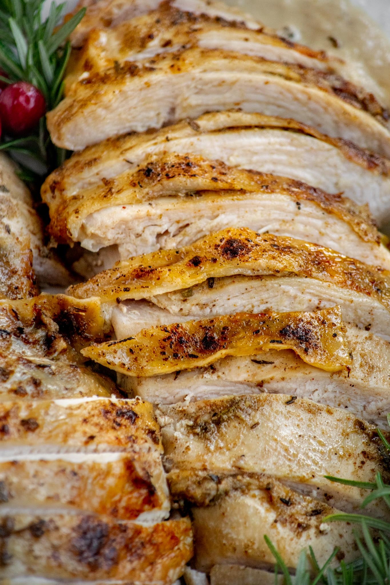 Close-up of juicy Crockpot turkey breast slices with golden, buttery skin and garlic herb seasoning.