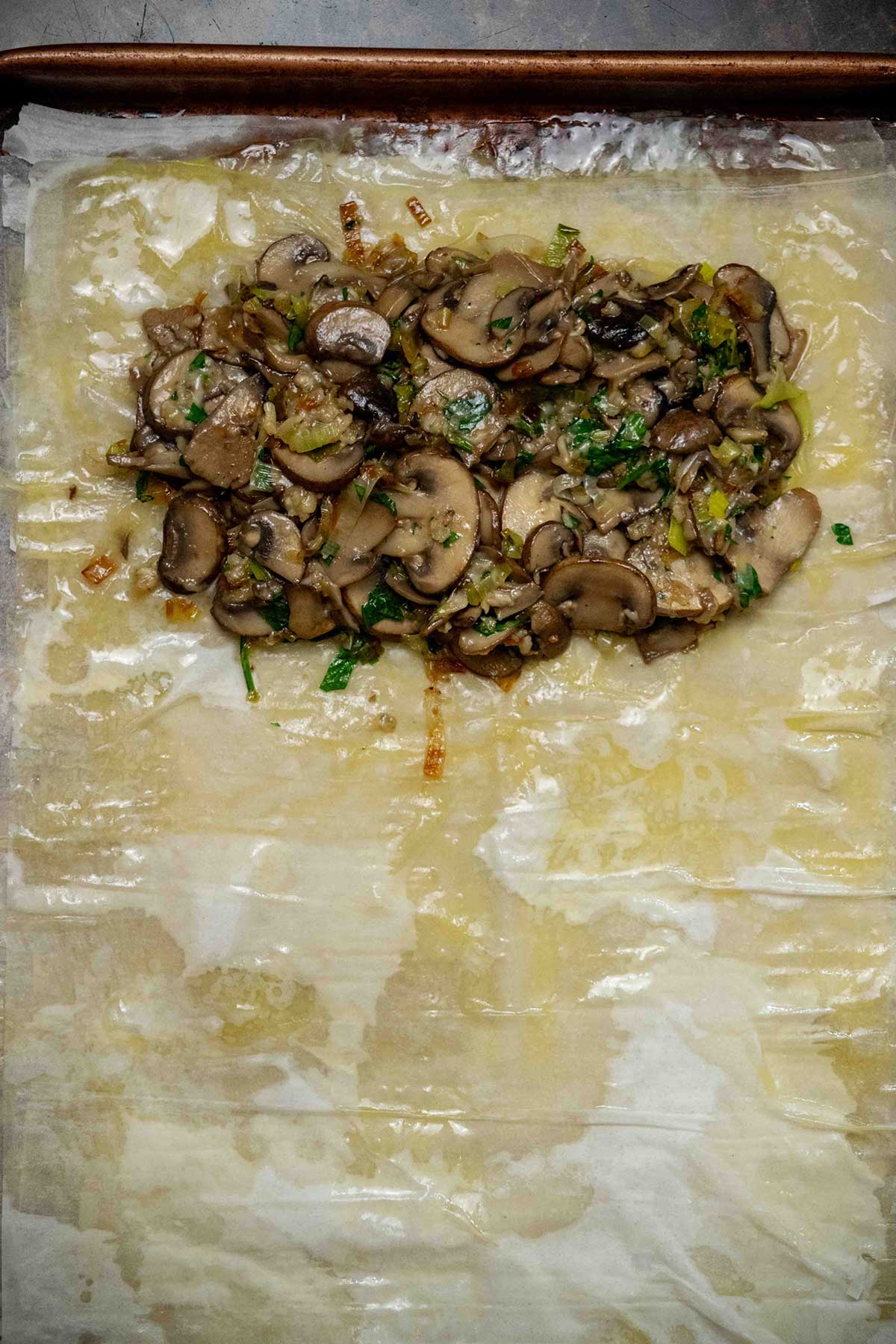 Assemble the strudel. Layer 4 sheets of phyllo dough, brushing each sheet with melted butter as you go. Brush the edges with beaten egg, then spoon the mushroom filling onto one end of the pastry, leaving a small border around the edges.