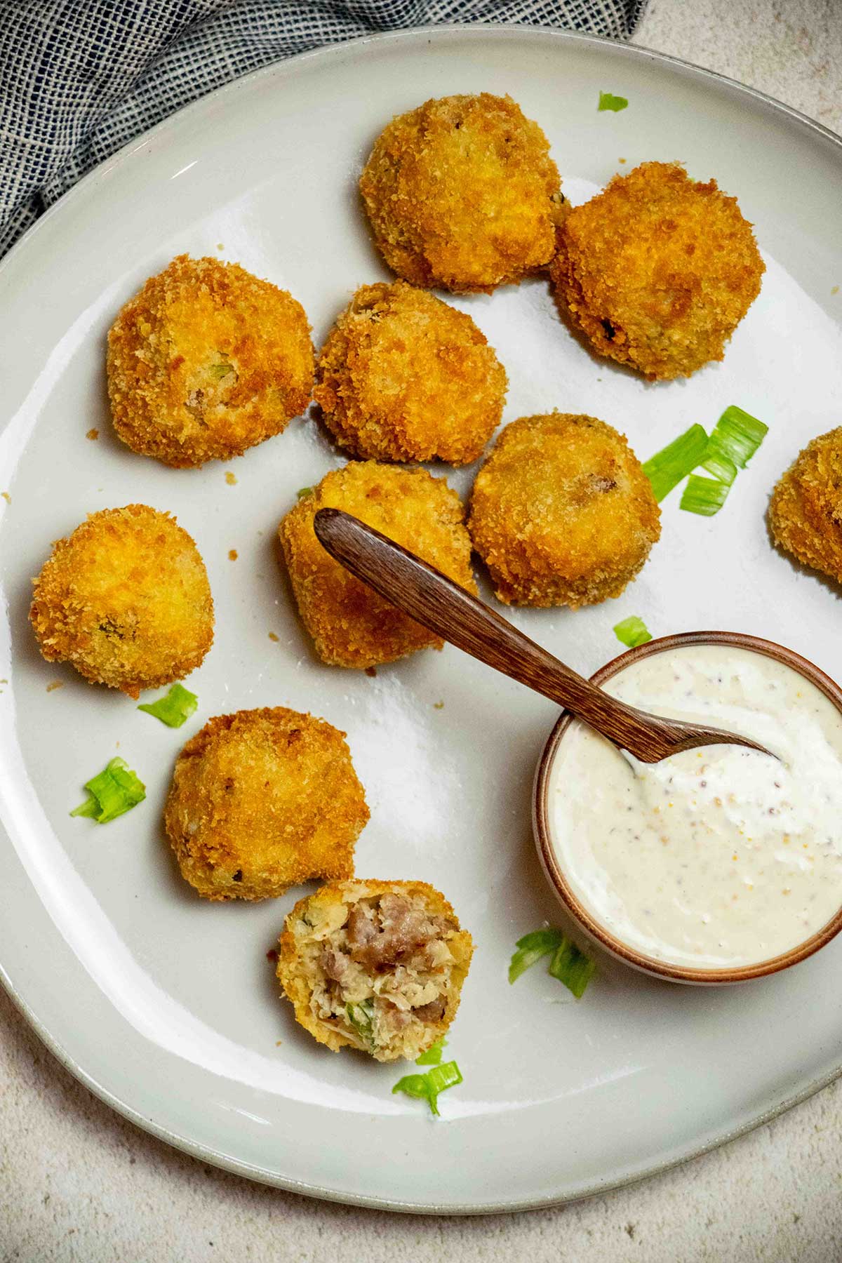 Overhead view of crispy sauerkraut balls with bratwurst and sauerkraut, served with whole grain mustard dipping sauce and sliced scallions.