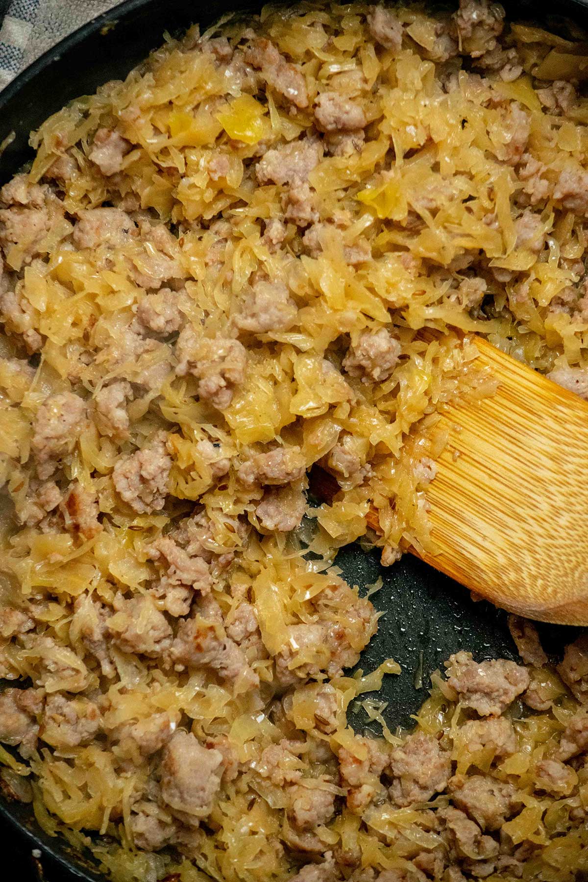 Cook the bratwurst and sauerkraut mixture. Remove the bratwurst from the casings and brown it in a skillet, breaking it up as it cooks. Add the drained, chopped sauerkraut, caraway seeds, beer, salt, and pepper, then cook until the liquid has evaporated.