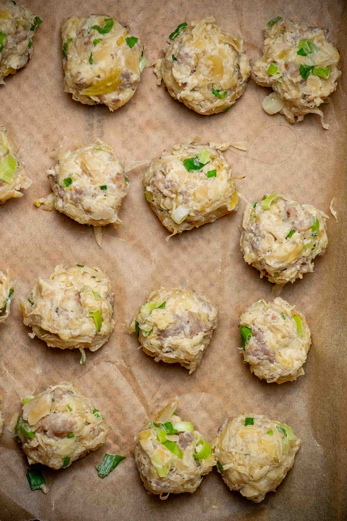 Form and chill the sauerkraut balls. Mix the cooked bratwurst and sauerkraut with softened cream cheese, panko, and scallions. Scoop into balls, place on a parchment-lined baking sheet, and refrigerate for at least 1 hour or up to overnight.