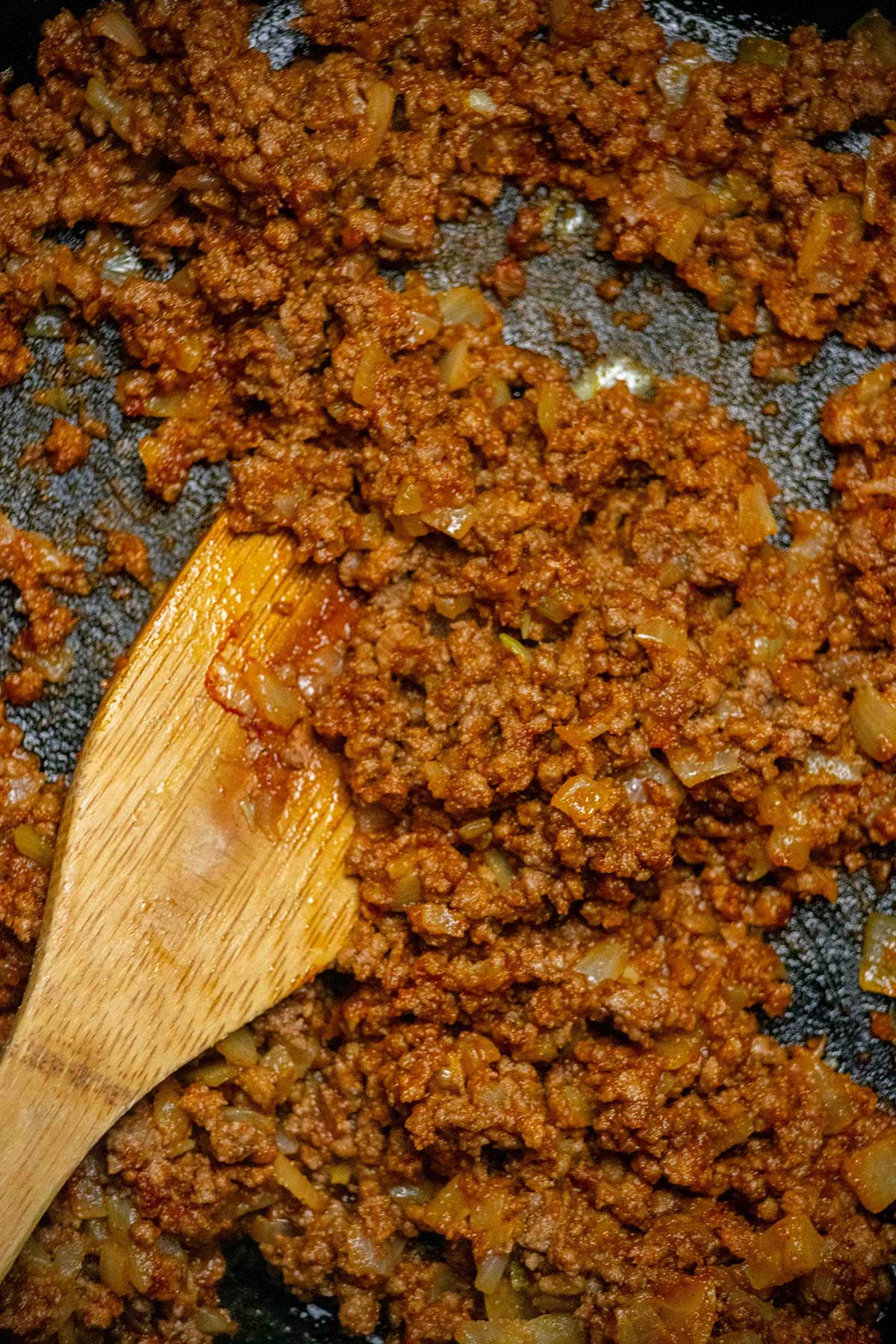 Brown the beef. Cook the onions in butter until softened, then add the ground beef and cook until browned. Stir in the tomato paste, seasonings, and flour until evenly combined.