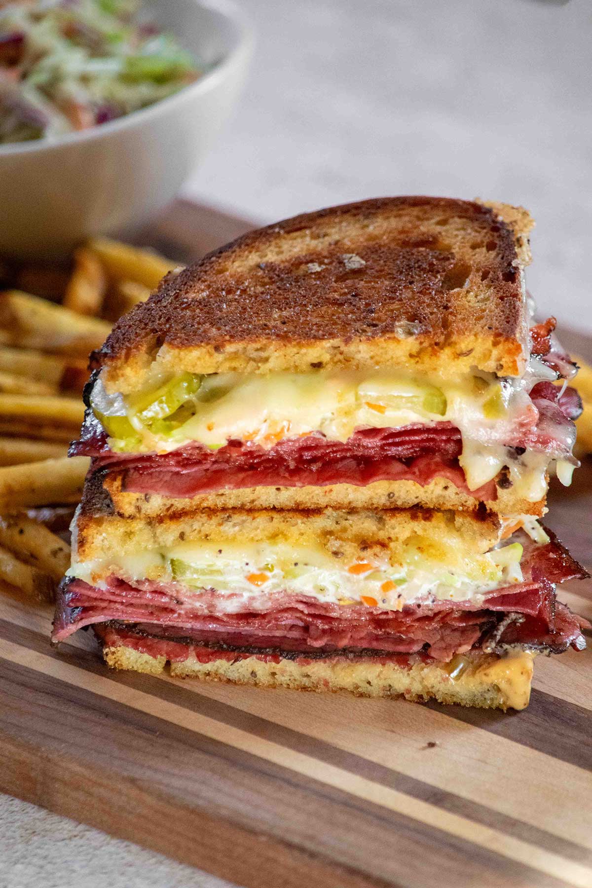 grilled pastrami sandwich with a side of fries and extra coleslaw on the side.