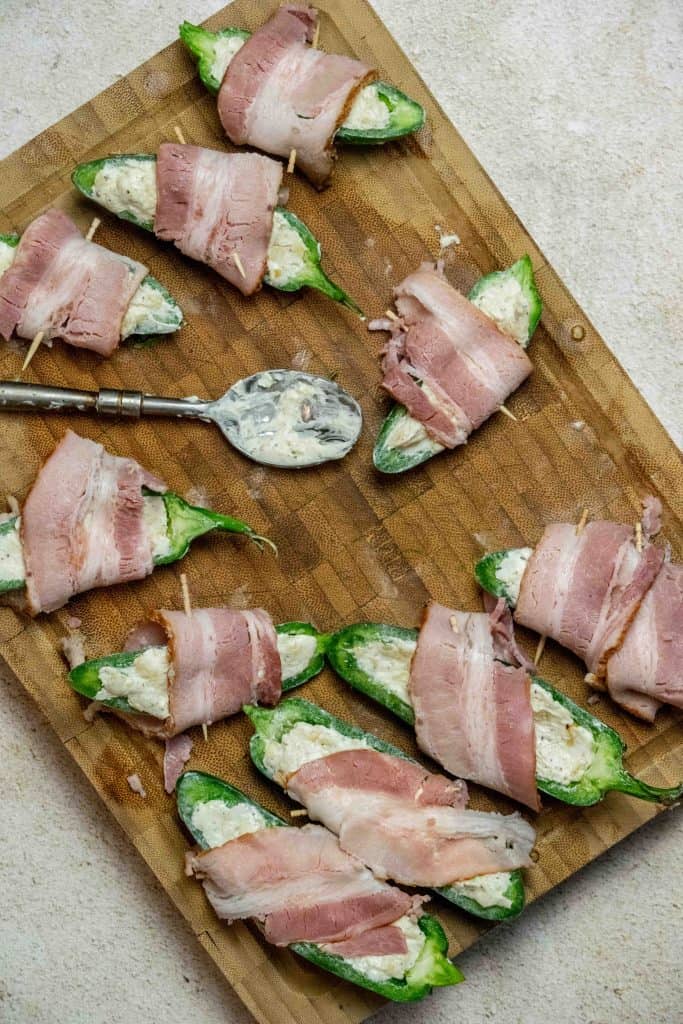 fill each pepper half with cream cheese mixture, wrap with bacon, and secure with toothpicks