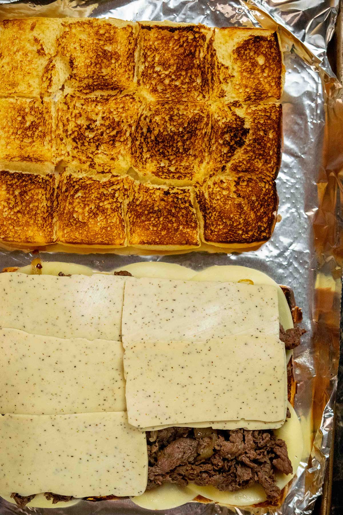 Assemble the sliders.
Using a slotted spoon, spread the steak and onions over the provolone, leaving excess liquid behind. Top with American cheese and the top half of the rolls.