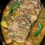 Slow cooker pork sirloin roast sliced in gravy with red potatoes, onions, and fresh rosemary.