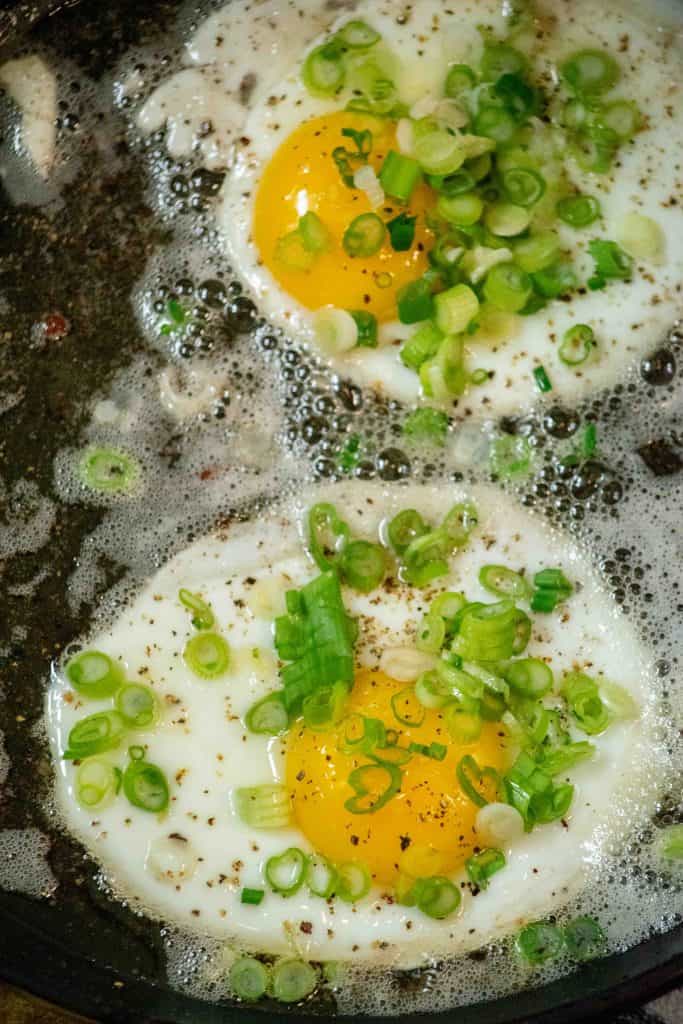 cook your. bacon to desired doneness in the same pan with black pepper, set aside to drain, and crack eggs into cooled pan on low heat and add scallions, salt and pepper once eggs start to set