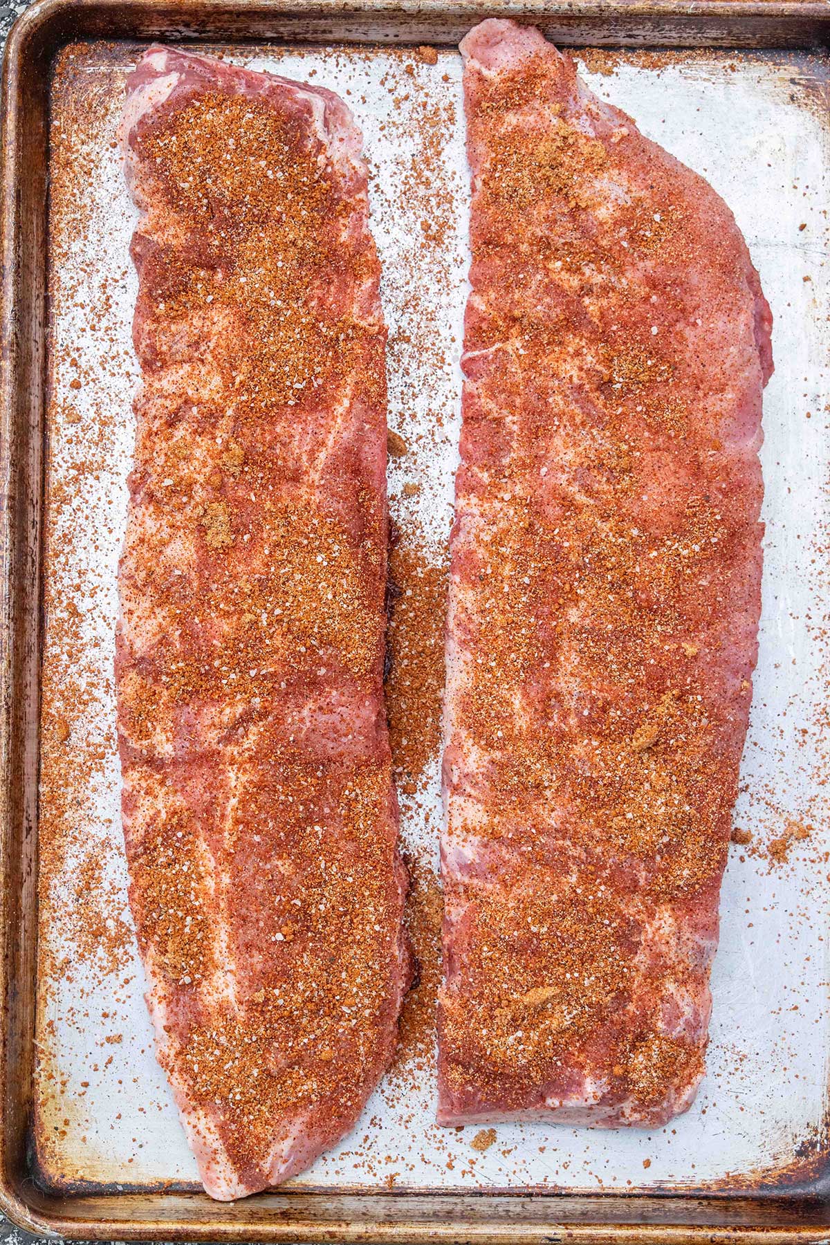 Rib dry rub on racks of baby back ribs.