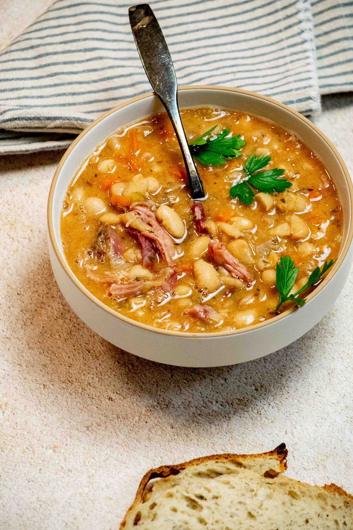 Slow cooker ham bone soup with white beans, carrots, celery and shredded ham in a bowl.