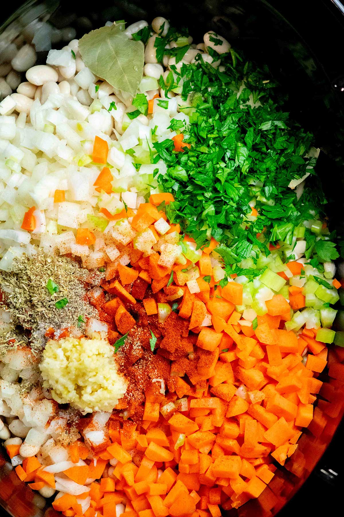 Add the ingredients. Add the soaked beans, vegetables, garlic, herbs, seasonings and broth to the slow cooker.