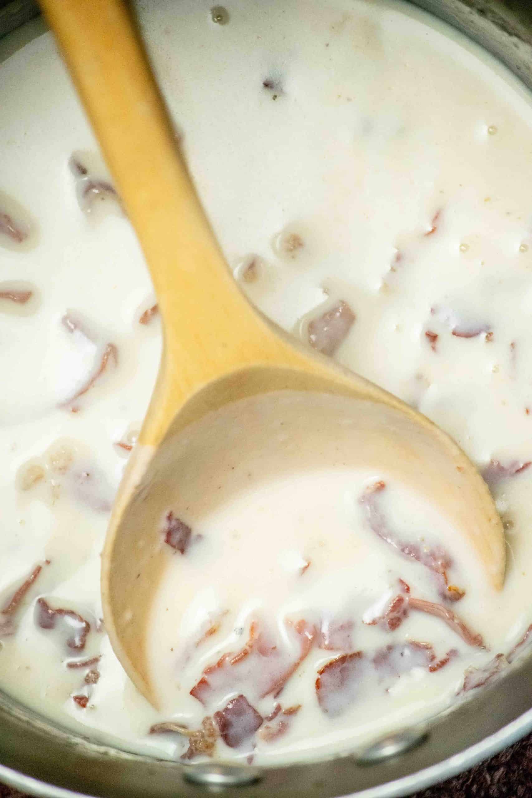 Milk added to the skillet and a wooden spoon stirring until smooth.