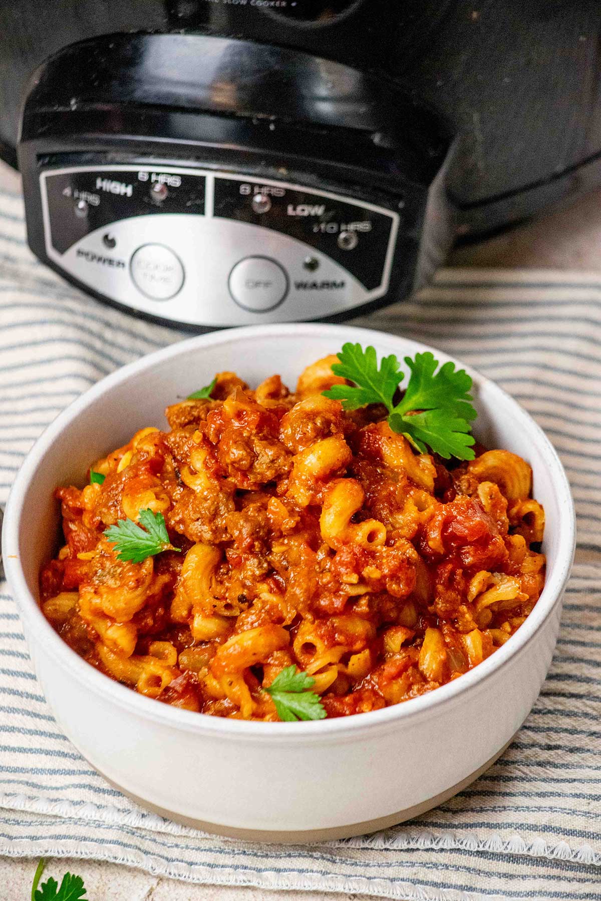 Crockpot Goulash Recipe in a bowl, garnished with parsley by Crockpot.