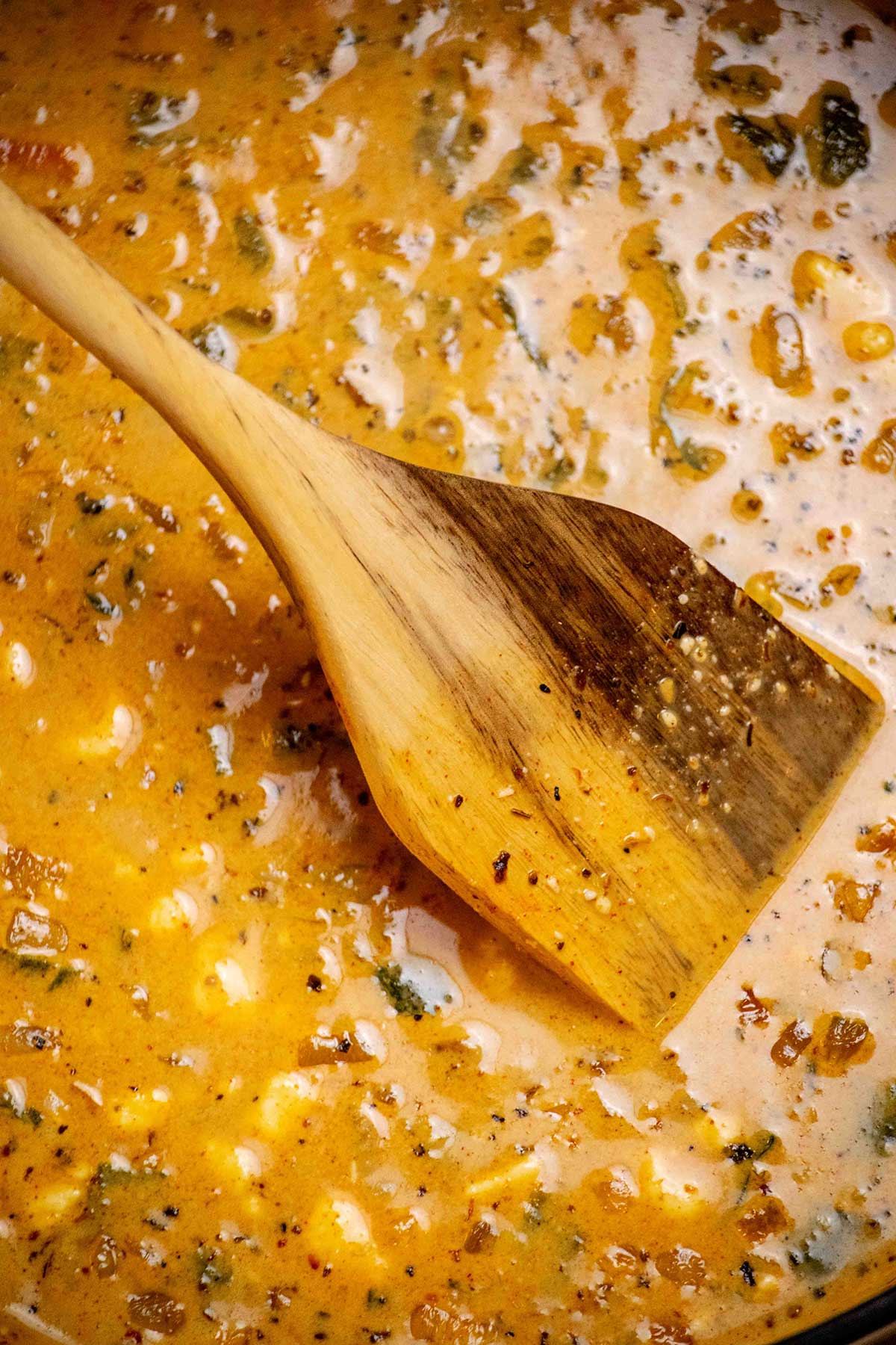 Build the soup base. Sauté the onion in butter, then add the garlic, spices, and roasted poblanos. Stir in the cream cheese and chicken broth.